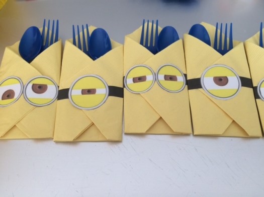 Minion Utensil Holder. I folded the yellow napkin. Printed the minion eyes onto a mailing label and used that as a sticker to hold the napkin together